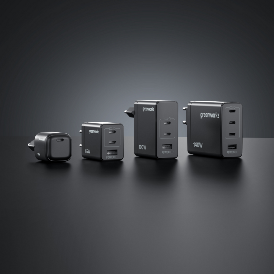 Four Greenworks power chargers of different sizes on a dark background