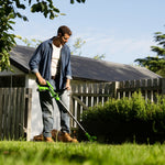 Man using a lawn mower in a garden with a wooden shed in the background