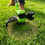 Green and black lawn trimmer being used on grass